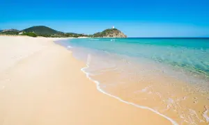 Piękne plaże Cagliari, z turkusową wodą i złotym piaskiem, zapraszają do relaksu. W oddali widać wieżę na wzgórzu.