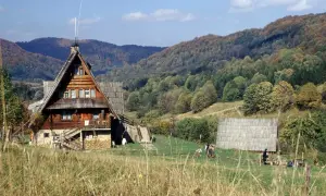 Drewniane schroniska górskie w Polsce, otoczone jesiennymi lasami. Ludzie odpoczywają na trawie, ciesząc się widokiem.