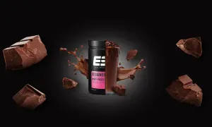 Schokoladenstückchen umgeben einen Becher Designer Whey Protein. Die Frage, ob Proteinpulver krebserregend ist, bleibt unbeantwortet.