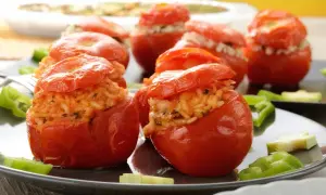 Pomodori ripieni di riso, un piatto gustoso e colorato, serviti su un piatto scuro con peperoni verdi.