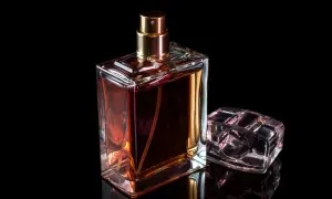 Elegancki flakonik baccarat perfume o bursztynowym kolorze, obok niego mniejszy, przezroczysty korek.