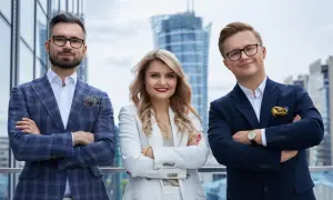 Trzy osoby w eleganckich garniturach stoją na tle nowoczesnych budynków.