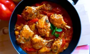 Un saporito pollo con peperoni in padella, con pezzi di pollo succulenti immersi in una ricca salsa rossa e verdure colorate.