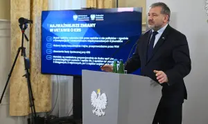 Mężczyzna przemawia przy mównicy z godłem Polski. Na ekranie za nim widnieje napis "Najważniejsze zmiany w ustawie o KRS", omawiający reformę neo KRS.