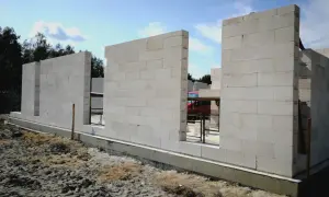 Budowa domu z bloczków z betonu komórkowego. Ściany wznoszą się nad fundamentem, tworząc zarys pomieszczeń.