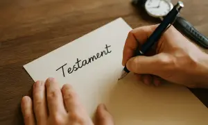 Ręka pisze długopisem słowo "Testament" na kartce. Ważne jest, jak napisać testament, by wszystko było jasne.