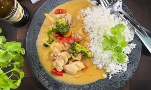 En smakrik thaigryta med kyckling, broccoli och paprika i en krämig sås, serverad med fluffigt ris.