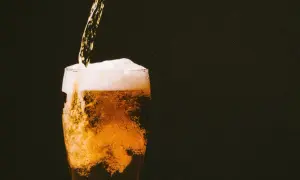 Birra dorata versata in un bicchiere, con schiuma abbondante e bollicine che salgono. Un piacere rinfrescante, ricco di sali minerali.