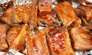Ania gotuje żeberka duszone w sosie barbecue. Mięso jest soczyste i apetyczne, przygotowane na folii aluminiowej.