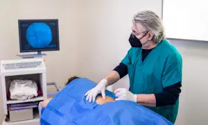 Un médecin réalise une infiltration du dos guidée par imagerie. Le patient est allongé, couvert d'un drap bleu.