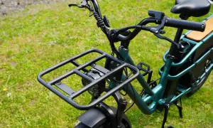 Zielony rower elektryczny dla seniora z dużą platformą bagażową z przodu i wygodnym siodełkiem. Idealny na zakupy i wycieczki.