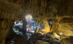 Interior de la cueva del Pindal, con estalactitas, rocas y escaleras iluminadas que conducen a la salida.