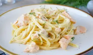 Spaghetti mit Lachs und Dill in cremiger Sauce auf einem Teller.