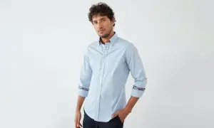 Ein Mann trägt ein hellblaues Hemd mit floralen Akzenten an Kragen und Manschetten. So lässt sich ein hellblaues Hemd kombinieren.