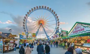 Buntes Treiben auf dem Frühlingsfest München mit Riesenrad, Essensständen und vielen Besuchern.
