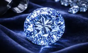 Olśniewający niebieski diament, lśniący na aksamitnym materiale. Obok leży lupa, gotowa do badania jego piękna.