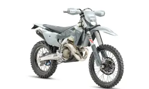 Szary motocykl Husqvarna z oponami terenowymi na białym tle.