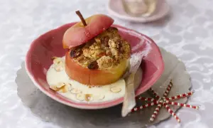 Ein köstlicher, veganer Bratapfel mit knuspriger Füllung und cremiger Soße, garniert mit Mandelsplittern.