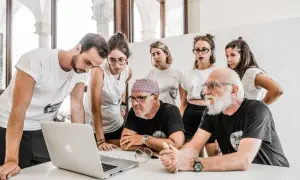 Stefano Guindani e un gruppo di giovani analizzano un progetto al computer, concentrati e seri.