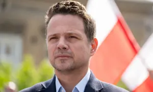 Rafał Trzaskowski, którego wiek jest często dyskutowany, na tle biało-czerwonych flag.