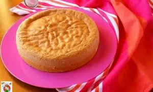 Gâteau Pan di Spagna, parfait pour une recette génoise moelleuse. Servi sur une assiette rose avec un torchon coloré.