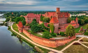 Malbork, największy zamek w Polsce, majestatycznie wznosi się nad rzeką Nogat. Jego ceglane mury i wieże świadczą o bogatej historii.