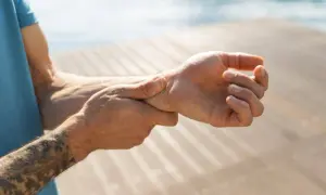 Mann hält sich das Handgelenk, da er Handgelenk schmerzen hat.