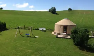 Une yourte confortable vous attend pour un séjour paisible en pleine nature, location yourte Jura. Balançoire et bancs invitent à la détente.