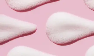 Delikatna piana z disodium laureth sulfosuccinate na różowym tle, tworząca miękkie, faliste kształty.