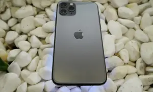 Szary iPhone 11 Pro leży na białych kamieniach. To urządzenie iPhone niedostępne, ale wciąż piękne.