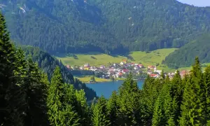 Idyllisches Dorf am See, umgeben von grünen Hügeln und Nadelwäldern. Perfekt für Slowakei Reisetipps!