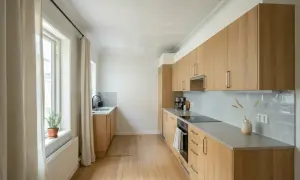 Ljust kök med ljusa träsnickerier, perfekt för att måla snickerier inomhus. Enkel inredning med diskbänk, spis och skåp.