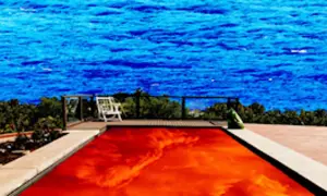 Płonący basen z wodą w kolorze czerwonym, jak na okładce Californication Red Hot Chili Peppers, na tle błękitnego morza.