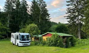 Wohnmobil neben bunten Hütten im Wald, ein idyllischer Ort nahe Banská Štiavnica.