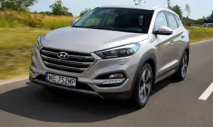Srebrny Hyundai Tucson 3 jedzie po drodze, otoczony zielenią.