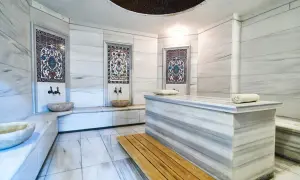 Wnętrze hammamu: marmurowe ściany, ozdobne kafelki, kamienne misy i ława. To miejsce relaksu i odnowy, gdzie poczujesz się jak w orientalnej łaźni.