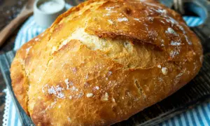 Ein frisch gebackenes, knuspriges Brot liegt auf einem Holzbrett. Perfekt für einfaches Brot backen.