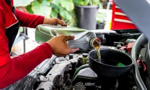 Mecánico vierte aceite nuevo en el motor de un coche, recordando que el aceite de coche caduca y debe cambiarse.