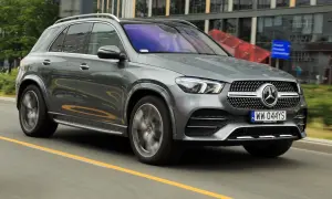 Szary Mercedes GLE 300d jedzie po drodze, w tle nowoczesne budynki.