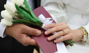 Para ślubna trzyma bukiet białych tulipanów i dokument.