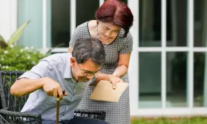 Una donna aiuta un uomo con bastone a rialzarsi. La speranza è che la paraplegia si può guarire, con supporto e cure.