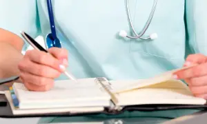 PKD ratownik medyczny notuje w notatniku. Stetoskop wisi na jego fartuchu.