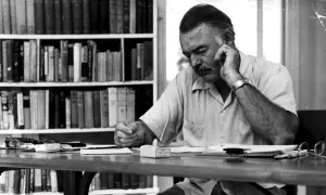 Ernest Hemingway pisze, myśląc o tym, komu bije dzwon. Streszczenie jego myśli widać w skupieniu na twarzy.