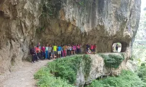 Grupo de excursionistas posa en la Ruta del Cares, superando la dificultad del terreno rocoso y los túneles.