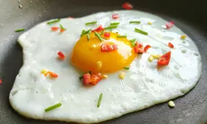 Jajko sadzone na patelni z posiekaną papryczką chili i szczypiorkiem.