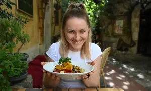 Uśmiechnięta kobieta prezentuje talerz z daniem, które wygląda jak pyszne dieta śródziemnomorska przepisy.