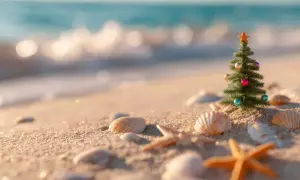 Ein kleiner Weihnachtsbaum mit bunten Kugeln und einem Stern steht am Strand. Perfekt für alle, die im Dezember Sonne statt Schnee suchen.