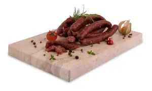 Kiełbaski wieprzowe, przyprawione pieprzem i ziołami, leżą na kamiennej desce. Z czego jest peperoni? Z mięsa i przypraw, a nie z tych składników.