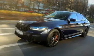 Ciemnoniebieskie BMW 540d w ruchu ulicznym, z widocznymi światłami LED i czerwonymi zaciskami hamulcowymi.
