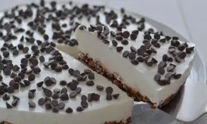 Una fetta di torta fredda allo yogurt, ricoperta di gocce di cioccolato, viene servita da una spatola.